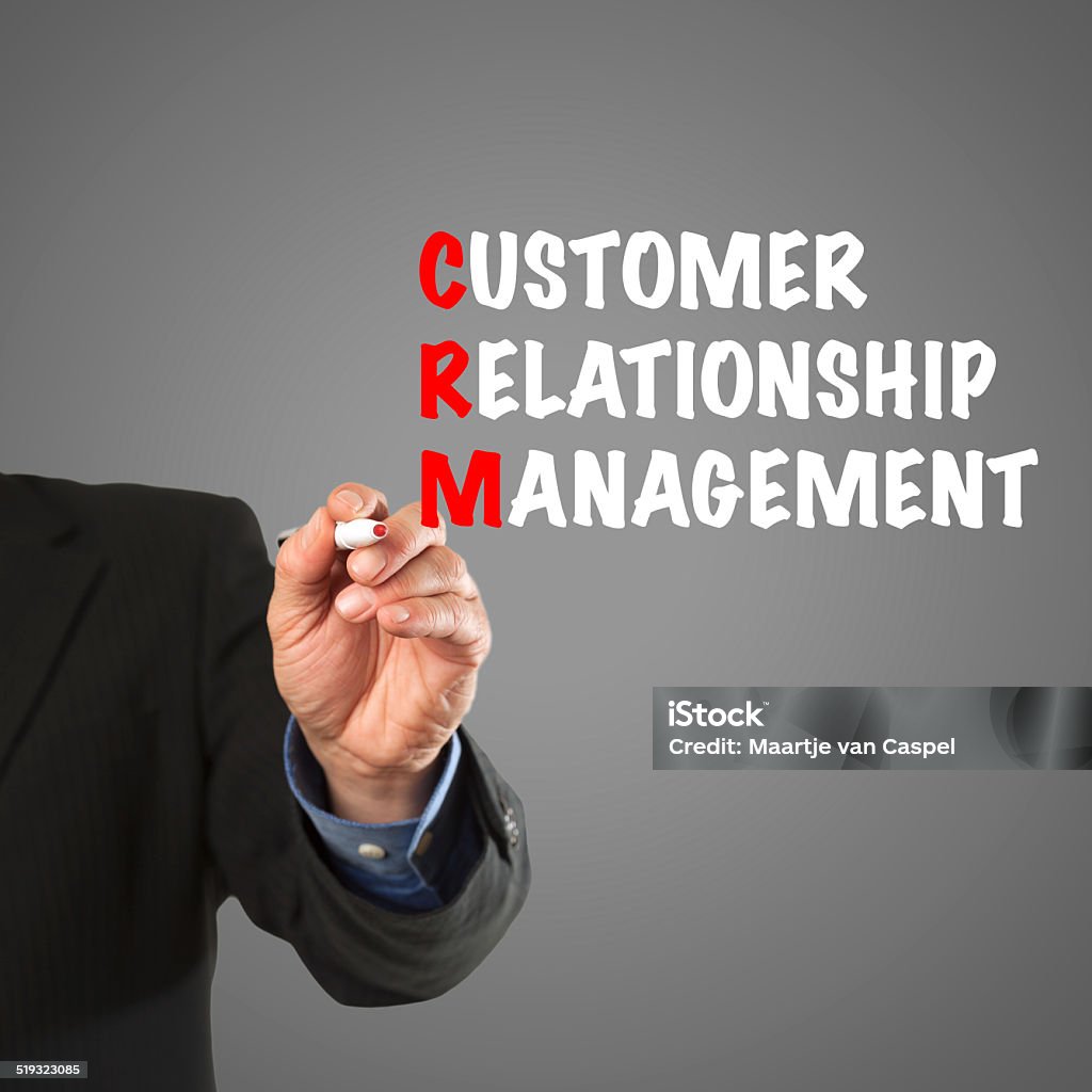 Business man hand writing CRM acronym Male hand in business wear holding a thick pen, writing the terms Customer Relationship Management acronym CRM. Acronym Stock Photo