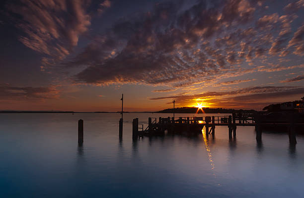 Sunset over a jetty near Brownsea Island in Poole Harbour Sunset over Brownsea Island in Poole Harbour, Dorset, the second largest natural harbour in the World sandbanks poole harbour stock pictures, royalty-free photos & images