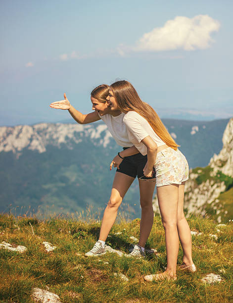 Showing direction in mountains Two girls on mountain top looking lanscape beautiful multi colored tranquil scene enjoyment stock pictures, royalty-free photos & images