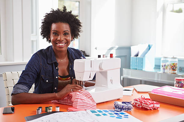 istock Young black woman using a sewing machine looking to camera 519329856