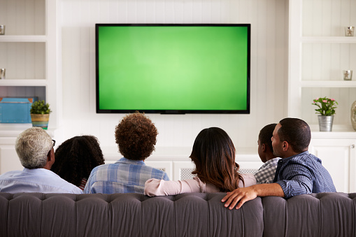 Multi generación familia viendo televisión en su casa, vista atrás photo