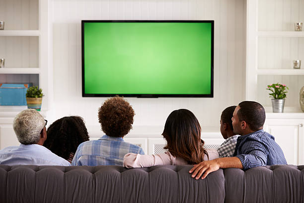 multi génération famille regardant la télévision à la maison, vue de derrière - groupe moyen de personnes photos et images de collection