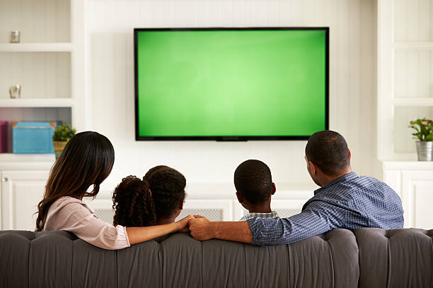 parents et ses deux enfants en regardant la télévision à la maison - regarder la télévision photos et images de collection