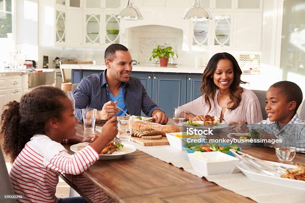 Padres y de sus dos niños comiendo en la mesa de la cocina - Foto de stock de Familia libre de derechos