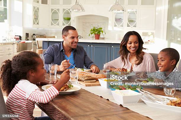 Padres Y De Sus Dos Niños Comiendo En La Mesa De La Cocina Foto de stock y más banco de imágenes de Familia