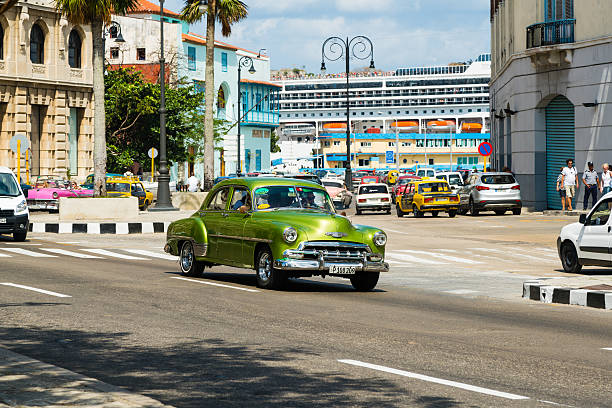 Vintage American car taxi on Avenida del Puerto, Havana, Cuba Havana, Cuba - February 23, 2016: Vintage American car taxi driving on Avenida del Puerto in Old Havana (La Habana Vieja), Havana, Cuba, Latin America. A large cruise ship MSC Opera coming to dock in Havana port in background. havana harbor photos stock pictures, royalty-free photos & images