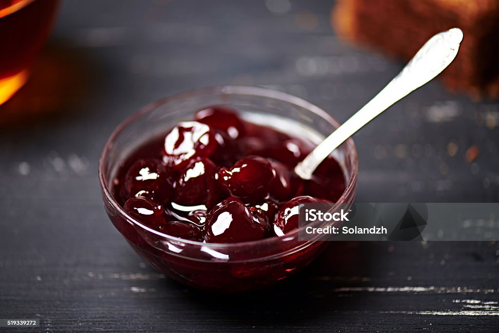 Cherry jam in a bowl Cherry jam in a glass bowl on a black wooden background. Close view. Shallow depth of field Berry Fruit Stock Photo