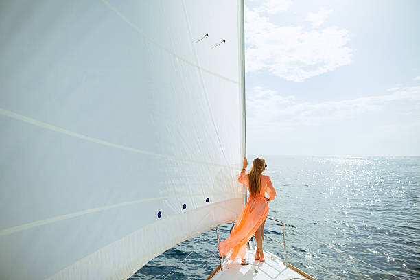 femme dans un paréo yachting ses voiles blanches de voyage de luxe - summer women fashion fashion model photos et images de collection