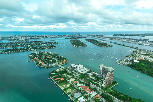 Row of three-storey houses with private docks in a coastal neighborhood at Miami, Florida. There is a small waterway on the left near the houses in an aerial shot view.