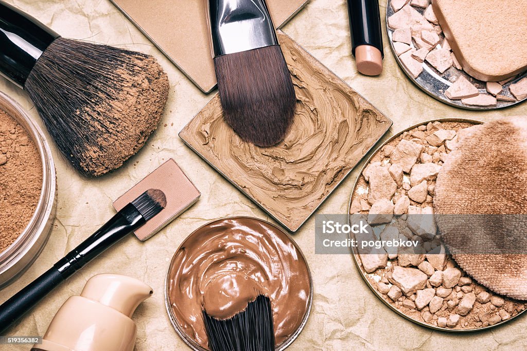 Makeup products to even out skin tone and complexion Makeup products to even skin tone and complexion on aged paper. Corrector, loose and compact powders, concealer pencil, liquid foundation with brushes and cosmetic sponges. Retro style processing Make-Up Stock Photo