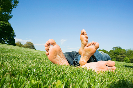 Young couple lying in grassy park, close-up of bare feet