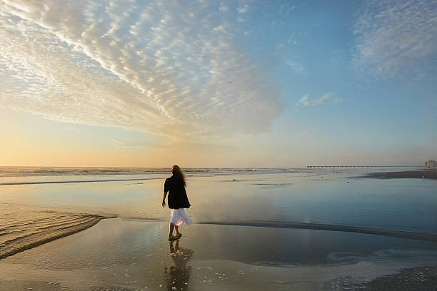 istock Woman walking on the beach at sunrise. 519360660