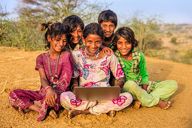 istock Happy Indian children using laptop, desert village, India 519360890