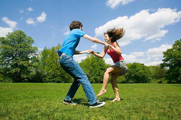 istock Young couple holding hands and dancing in park 519361843