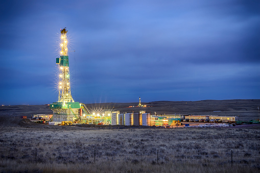 Evening shot of an oil Fracking Drill Rig with natural lens flaresFracking Oil Well is conducting a fracking procedure to release trapped crude oil and natural gas to be refined and used as energy