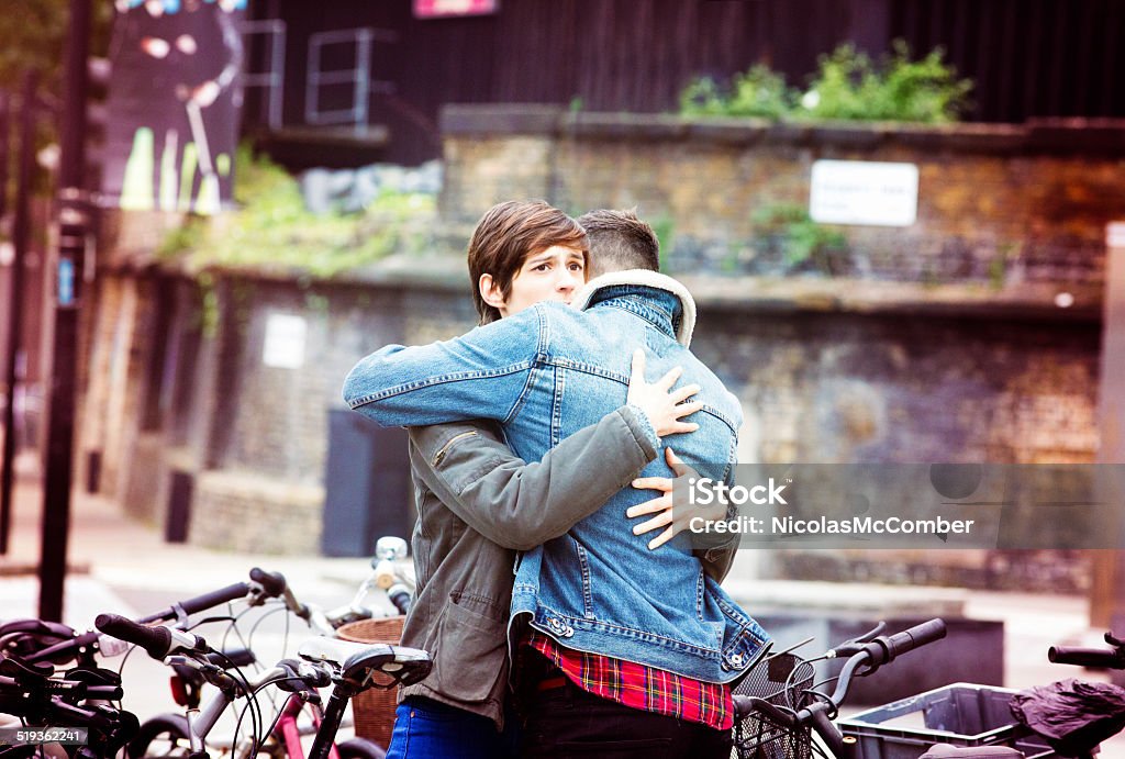 Urban Hug A young woman hugs a young man with a sad expression. Forgiveness Stock Photo