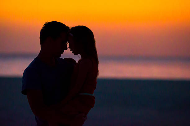 istock Family silhouette in the sunset at the beach 519362802