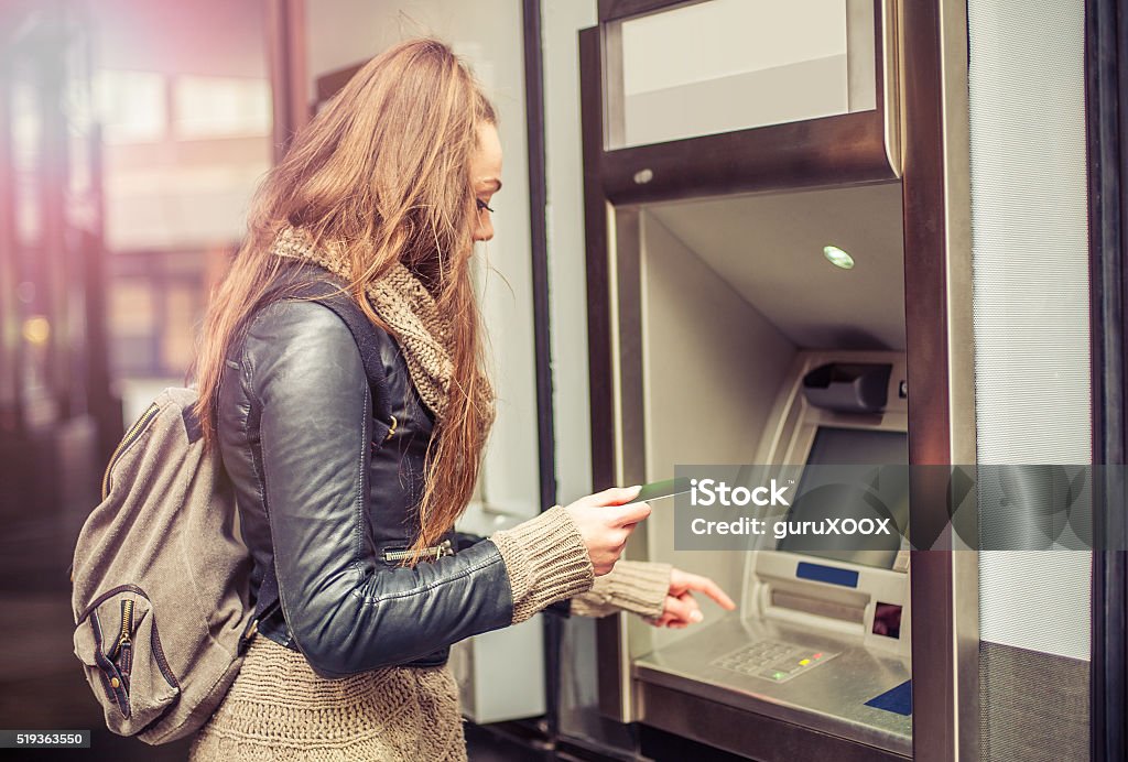 Young woman taking money from ATM Young woman withdrawing money from credit card at ATM Student Stock Photo