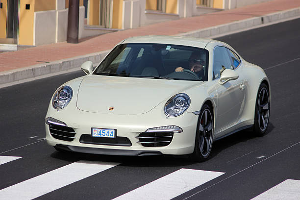 Porsche 911 50th anniversary edition in Monte-Carlo, Monaco Monte-Carlo, Monaco - April 6, 2016: Porsche 911 Carrera S on Avenue d'Ostende in Monaco. Man Driving an Expensive White Porsche 911 50th anniversary edition in the south of France 50th anniversary photos stock pictures, royalty-free photos & images