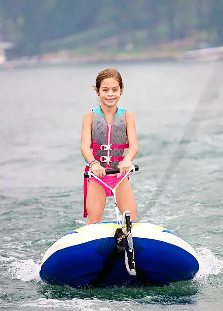 Smiling young girl riding behind a boat on a lake. Summer fun