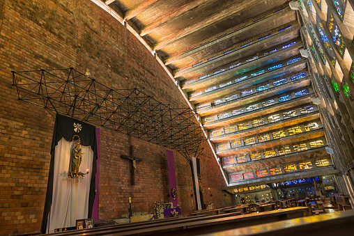 San Salvador, El Salvador - December 22, 2015:From the outside it resembles a concrete airplane hangar with a dome shaped roof, but inside at sundown the stained glass in the ceiling filters the light in a rainbow of color that splashes across the alter.  