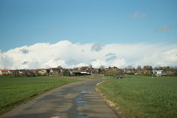 Driving on Ile de France roads on a sunny afternoon just after rain, and entering a small typical village. France