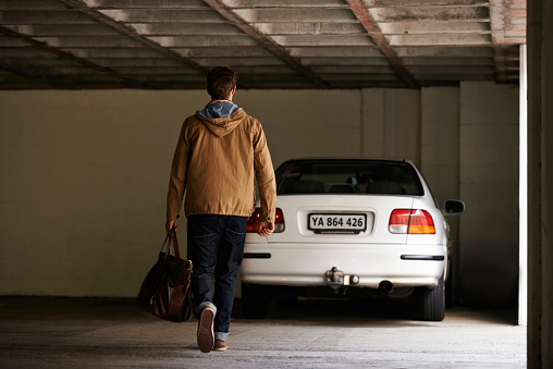 Rearview shot of a man walking towards his parked car in a garage
