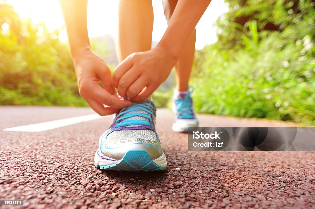 woman runner tying shoelaces on trail young fitness woman runner  tying shoelaces on trail Adult Stock Photo