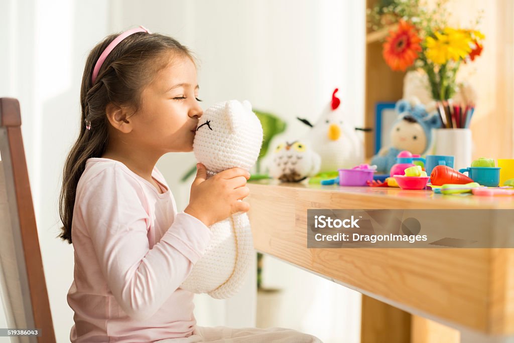 Girl with toy cat Little girl kissing her knitted cat Child Stock Photo