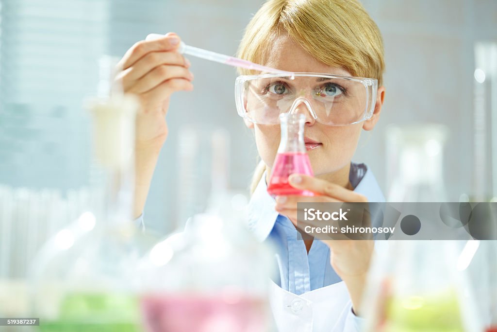 Working with liquids A young chemist holding tubing with liquid during chemical experiment Adult Stock Photo
