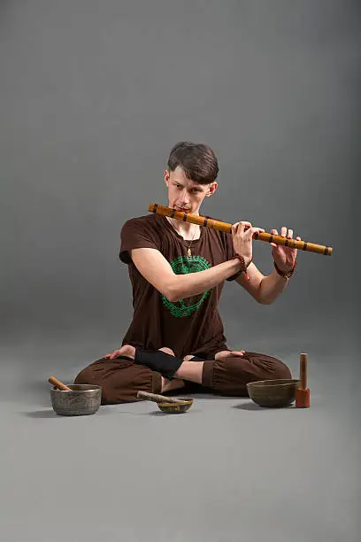 Man playing the flute, singing bowls and tools for meditation.