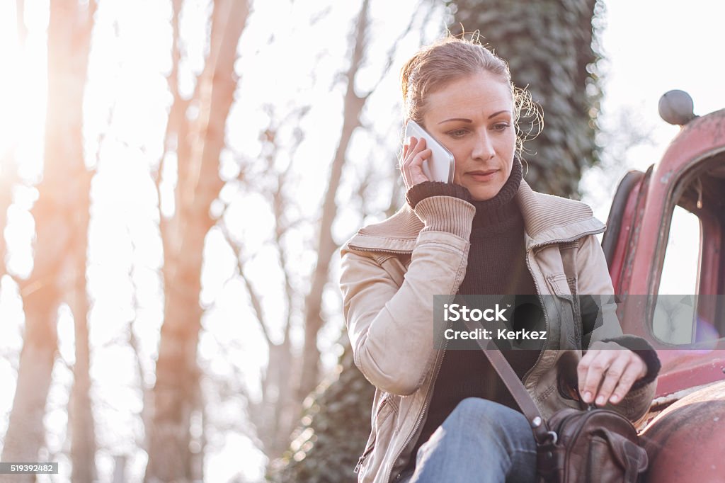 Woman talking on smart phone Woman sitting on the old car and talking on smart phone Abandoned Stock Photo