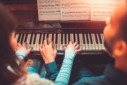 Young adults playing piano together.