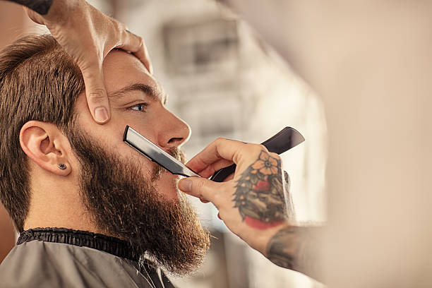 Barber with old-fashioned black razor Barber with old-fashioned black razor shaving bearded man barber stock pictures, royalty-free photos & images