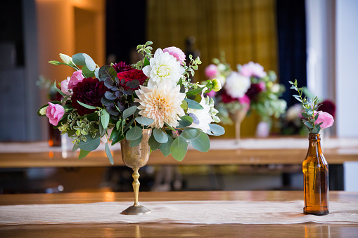 Wedding flowers on reception tables setup by a florist using vintage antique bottles.