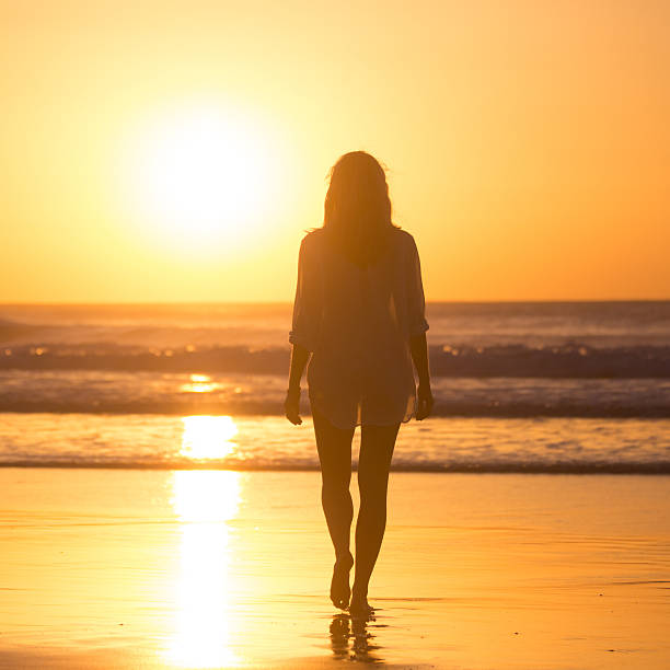 istock Lady walking on sandy beach in sunset. 519402326