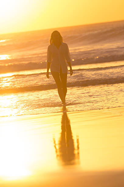 istock Lady walking on sandy beach in sunset. 519402408