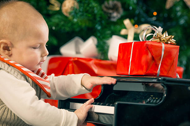 istock Little boy playing little piano with red christmas present 519404451