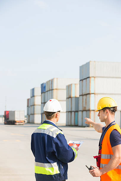 istock Rear view of male workers discussing in shipping yard 519409721