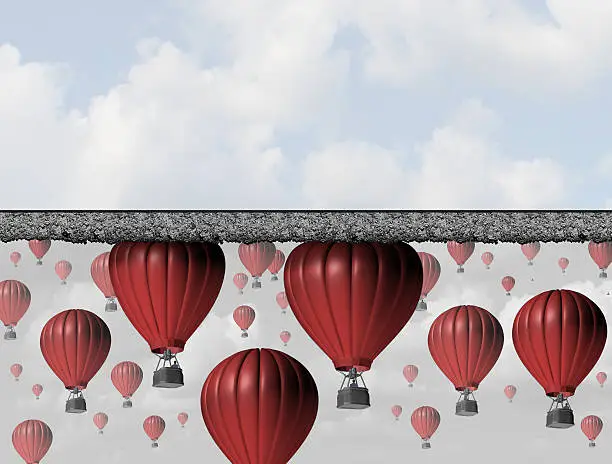 Hitting a wall and reach the limit or ceiling as a business concept for restricted opportunity and closed economic barrier to succeed as a group of air balloons trapped by a thick roof.