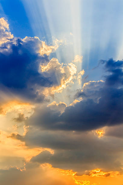 Clouds and a blue sky with a sunbeam shining through.