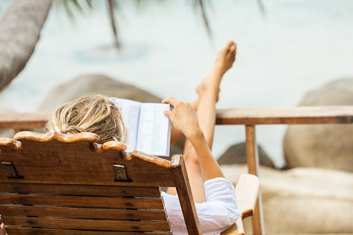 Young woman reading a book while relaxing on tropical island. Koh Phangan island, Thailand