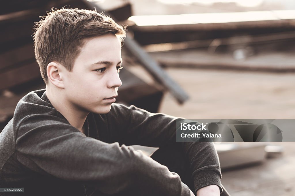 Pensive teenager sitting on the roof of the house Lonely teenager sitting on roof the house Adolescence Stock Photo