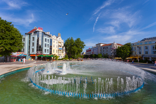 Varna, Bulgaria - June 4, 2011: A fountain sitting in the middle of a commercial district in Varna, Bulgaria. People can be seen walking around in the background.