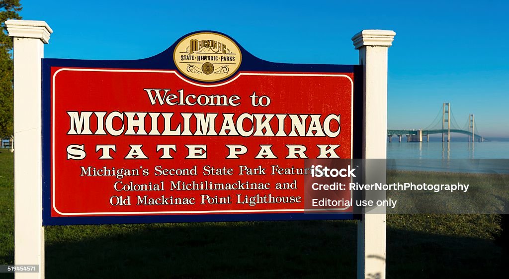 Michilimackinac State Park Mackinac City, Michigan, USA - September 27, 2014: A sign welcoming visitors to Michilimackinac state park with people and traffic on Mackinac Bridge in the background. American Culture Stock Photo