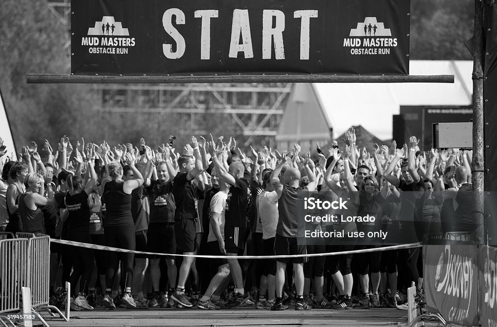 Participants with hands in air at start of mud run Biddinghuizen, The Netherlands - September 28th 2014: Large group of participants gathered at the start of the Mudmasters event on Sunday 28th September 2014 in Biddinghuizen, The Netherlands. Adult Stock Photo