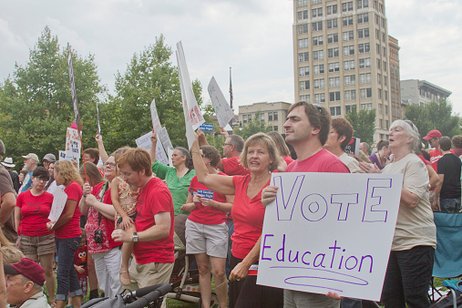 Asheville, North Carolina, USA - August 4, 2014: Moral Monday political rally demonstrators hold signs protesting education legislation and budget cuts and urge people to vote on August 4, 2014 in downtown Asheville, North Carolina