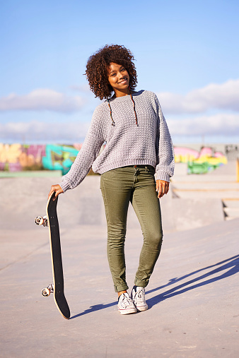 A young woman relaxing while holding her skateboard