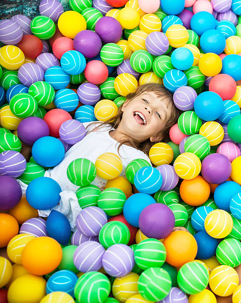 Girls in ball pool Happy child playing in pool with colored balls evening ball stock pictures, royalty-free photos & images