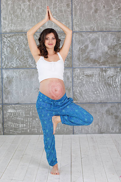 Pregnant girl is standing in yoga pose stock photo